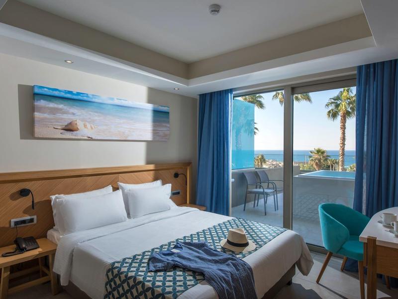 Nowoczesny pokój hotelowy z łóżkiem, balkonem i widokiem na morze w świetle dziennym.