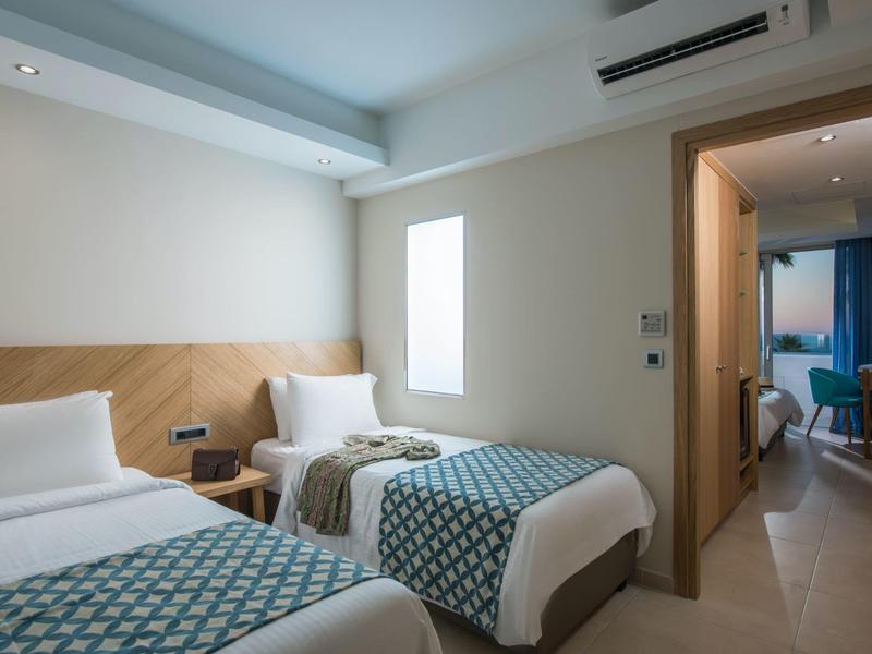 Nowoczesny pokój hotelowy z dwoma pojedynczymi łóżkami i jasnymi ścianami.