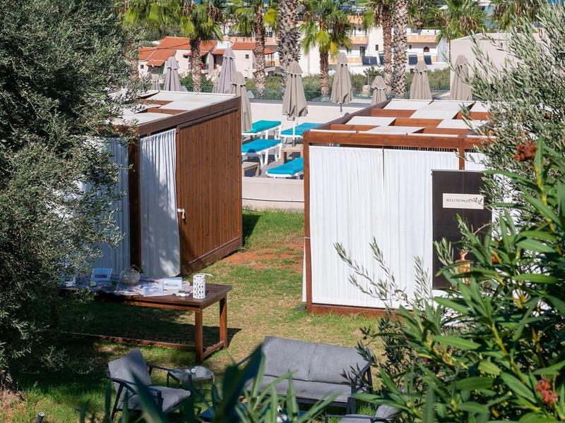 Nowoczesne bungalowy z palmami i basenem na tle błękitnego morza w słonecznym krajobrazie.