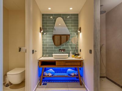 Moderní koupelna s umyvadlem, zrcadlem, toaletou a sprchou v hotelu.
