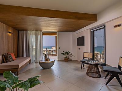 Moderní lounge hotelového pokoje s dřevěnými stěnami, sezením a výhledem na moře.
