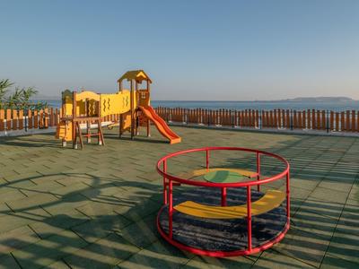 Área de juegos infantiles con tobogán y estructura para escalar en una azotea con vista a montañas.