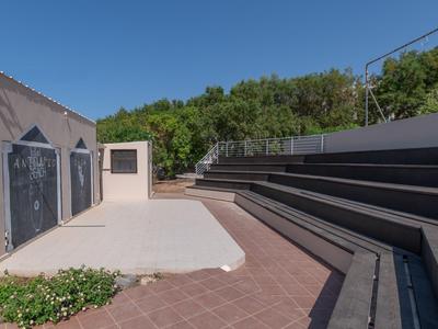Buitentheater met trapvormige zitplaatsen en bos op de achtergrond onder een blauwe lucht.