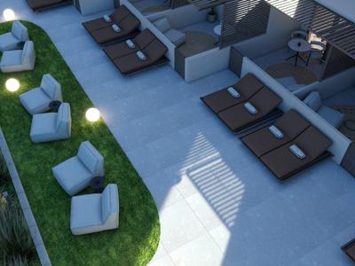 Diseño moderno de terraza de hotel con sillones al aire libre sobre césped y tumbonas sobre suelo de hormigón a la luz del atardecer