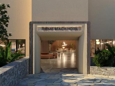 Ingang van een modern hotel met verlicht bord en omgeving met stenen pad.