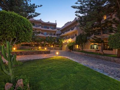 Verlicht hotelgebouw met tuin en geplaveid pad bij schemering