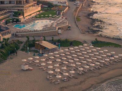 Hotel de playa con sombrillas y mar tranquilo al atardecer.
