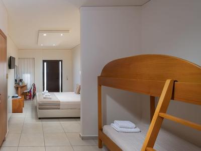 Habitación de hotel sencilla con litera, cama doble y muebles de madera en tonos neutros.