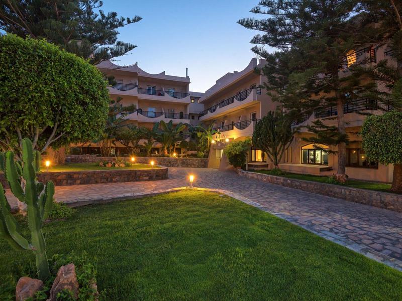 Jardín iluminado de hotel con césped cuidado y árboles al anochecer