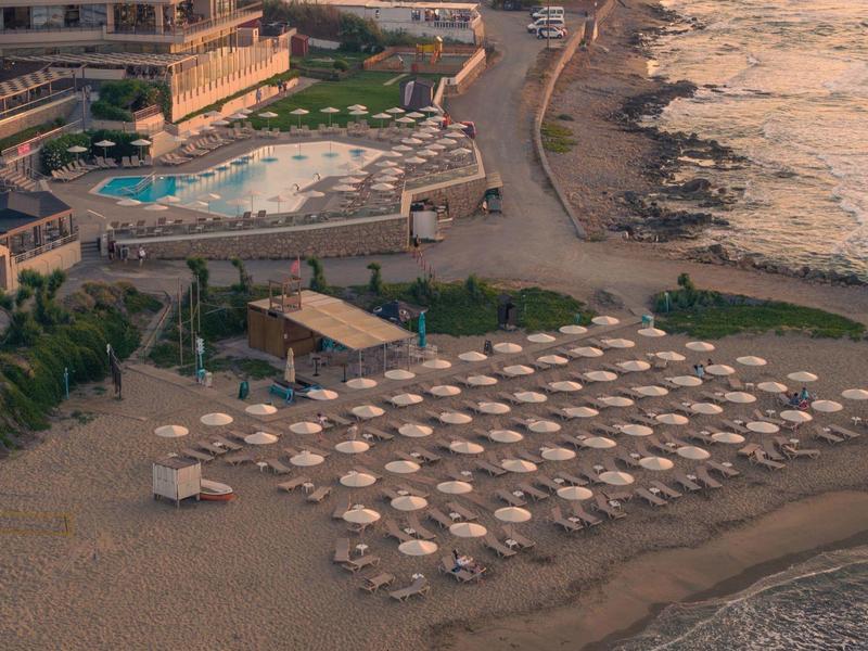 Hotel de playa con sombrillas y mar tranquilo al atardecer.