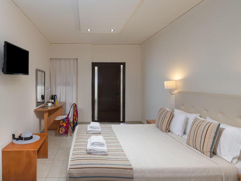 Habitación moderna de hotel con cama doble, TV, escritorio y luz cálida para una estancia cómoda.