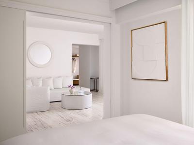 Jasny, nowoczesny pokój hotelowy z białymi meblami i minimalistycznym wystrojem.