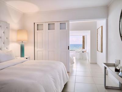 Jasna, nowoczesna sypialnia z widokiem na morze przez otwarte przesuwne drzwi.