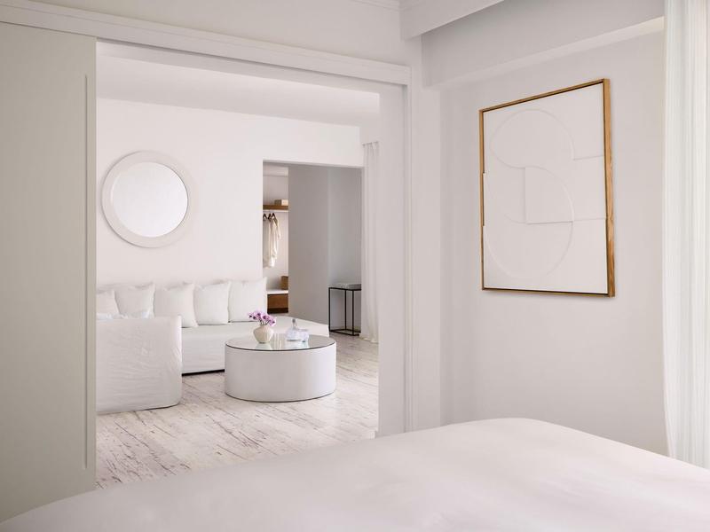 Jasny, nowoczesny pokój hotelowy z białymi meblami i minimalistycznym wystrojem.