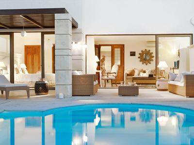 Área moderna de hotel con piscina iluminada y zonas de estar frente a grandes paredes de cristal.