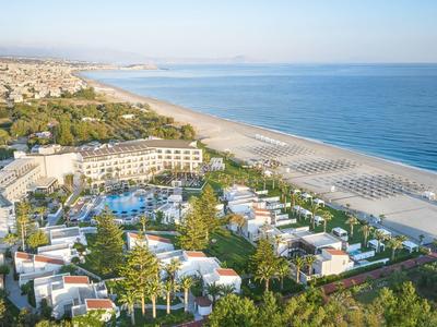 Vista de un resort con piscinas, pabellones y una larga playa de arena junto al mar.