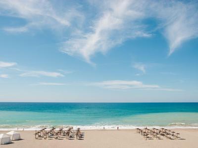 Szeroka piaszczysta plaża z leżakami i błękitnym niebem nad morzem