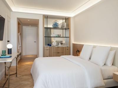 Camera d'hotel moderna con letto matrimoniale, scrivania e illuminazione elegante.