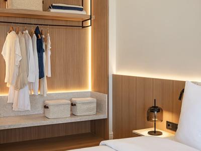 Armadio moderno con illuminazione a LED, spazio appendiabiti e scatole per riporre in una camera d'hotel.