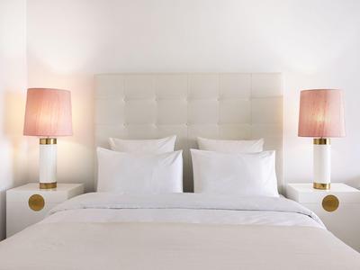 Letto d'hotel simmetrico con biancheria bianca e due lampade da comodino in una stanza moderna.