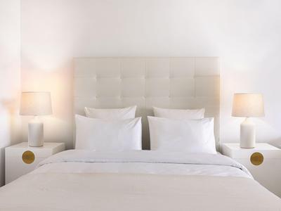 Camera luminosa con letto grande, cuscini bianchi e comodini con lampade.