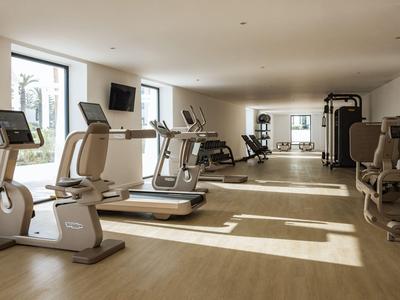 Palestra luminosa con tapis roulant, attrezzi e pavimento in legno.