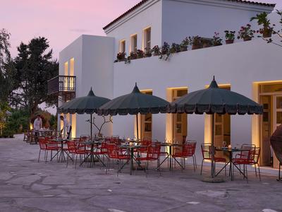 Terrazza dell'hotel con ombrelloni verdi e sedie rosse al tramonto.