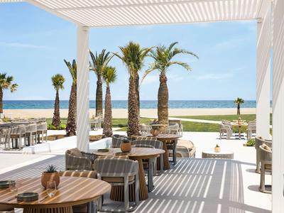 Area terrazza moderna con mobili in legno e metallo, palme e vista sul mare.
