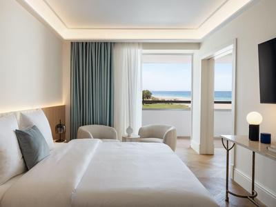 Camera d'hotel luminosa con letto grande, balcone e vista mare.