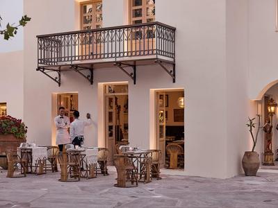 Cortile dell'hotel con tavoli e due persone davanti a un edificio con balcone.