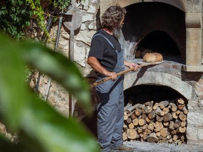 Una persona usa un forno a legna all'aperto in un hotel per cuocere il pane.