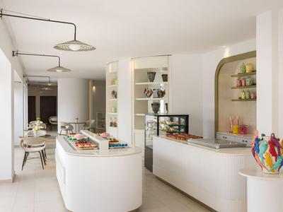 Area buffet di hotel moderna e luminosa con arredamento bianco e dettagli decorativi.