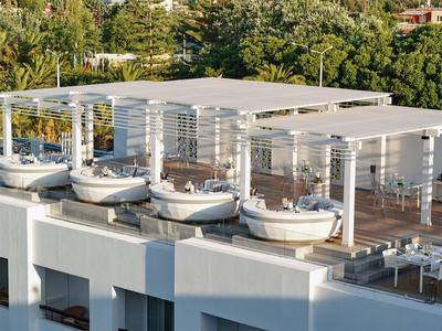 Terrazza sul tetto di un hotel con diverse aree coperte e vegetazione rigogliosa.