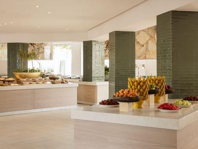 Buffet moderno con ciotole di frutta e arredamento neutro in una sala ristorante luminosa dell'hotel.