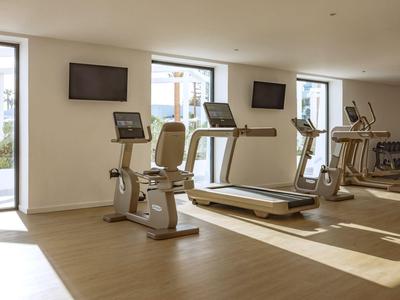 Palestra luminosa con tapis roulant, cyclette e ellittica vicino a grandi finestre.