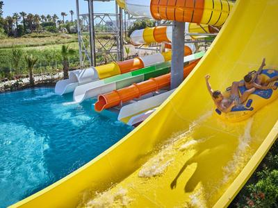 Due persone scivolano su uno scivolo d'acqua giallo in un parco acquatico.