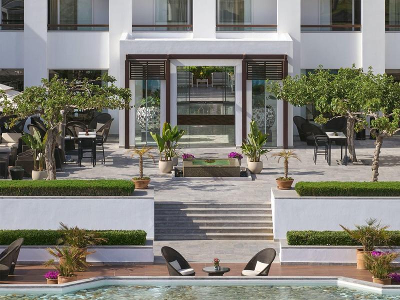 Área exterior moderna de un hotel con asientos, escaleras y plantas