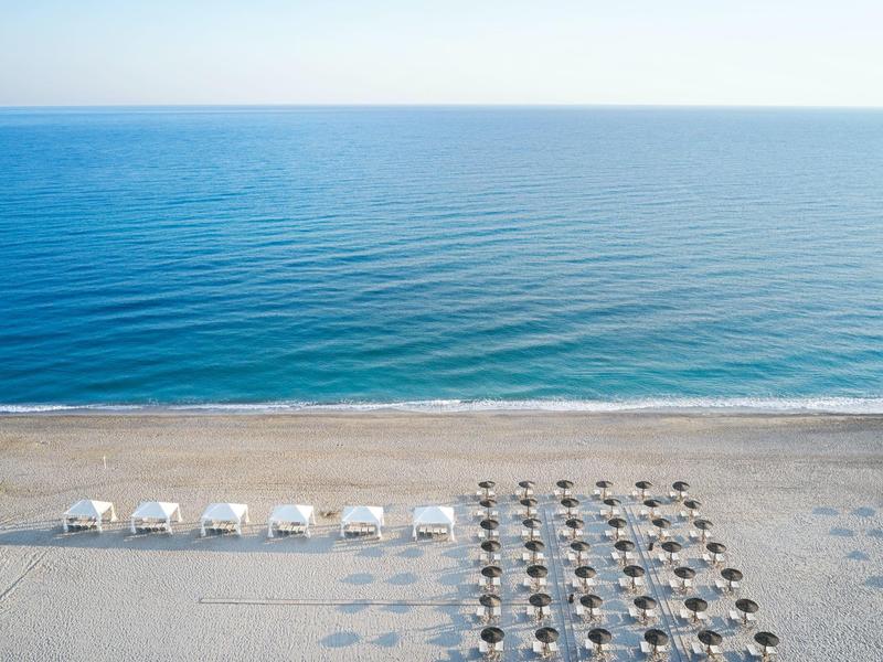 Distribución de sombrillas y tiendas de playa en una tranquila playa de arena junto al mar sereno