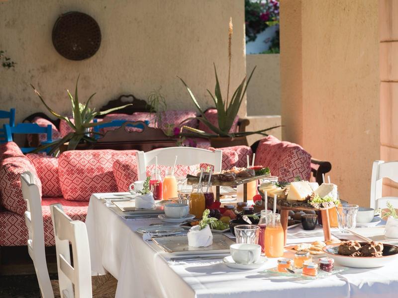Una mesa de desayuno puesta con jugos, café y pasteles en un acogedor patio.