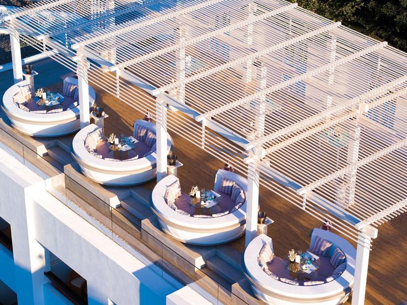 Terraza en la azotea con áreas de descanso redondas y pérgola en un hotel