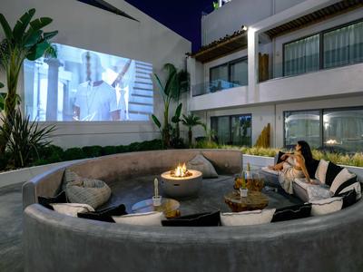 Gezellige buitenzitplek met vuurschaal en projectiescherm bij een modern hotel 's nachts.