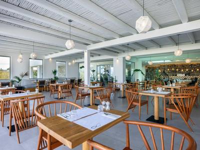 Restaurant lumineux et moderne avec meubles en bois et grandes fenêtres dans un hôtel.