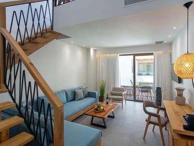 Salon moderne avec escalier en bois, canapé bleu et balcon avec coin salon.