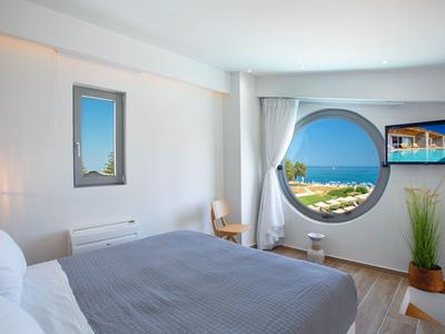 Bright hotel room with a large round window and sea view.