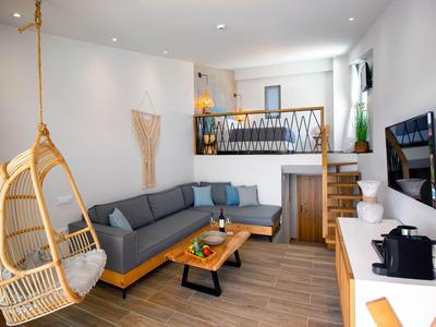 Modern living room with large corner sofa, hanging chair, and wooden staircase to a loft.