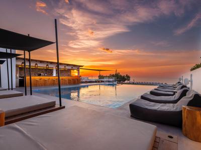 Modern pool area at sunset with lounge chairs and stylish lighting.