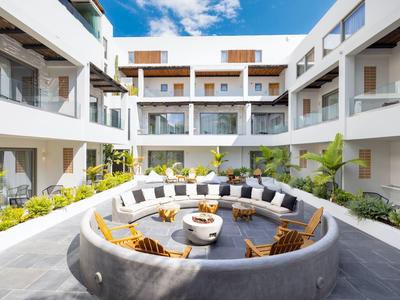Modern hotel courtyard with a circular seating area and plants, surrounded by balconies.