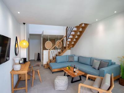 Modern hotel living area with corner sofa, wooden staircase, and balcony.