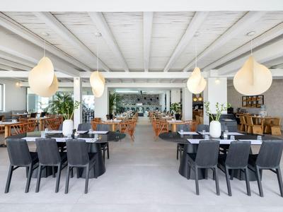 Modern open dining area with black chairs and hanging lamps in a hotel.