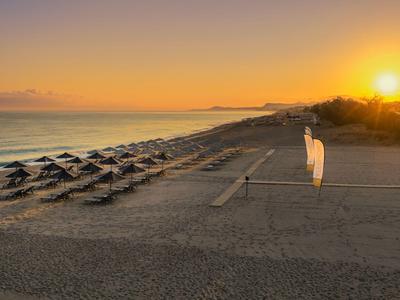 Empty beach with sun umbrellas and volleyball net at sunset.
